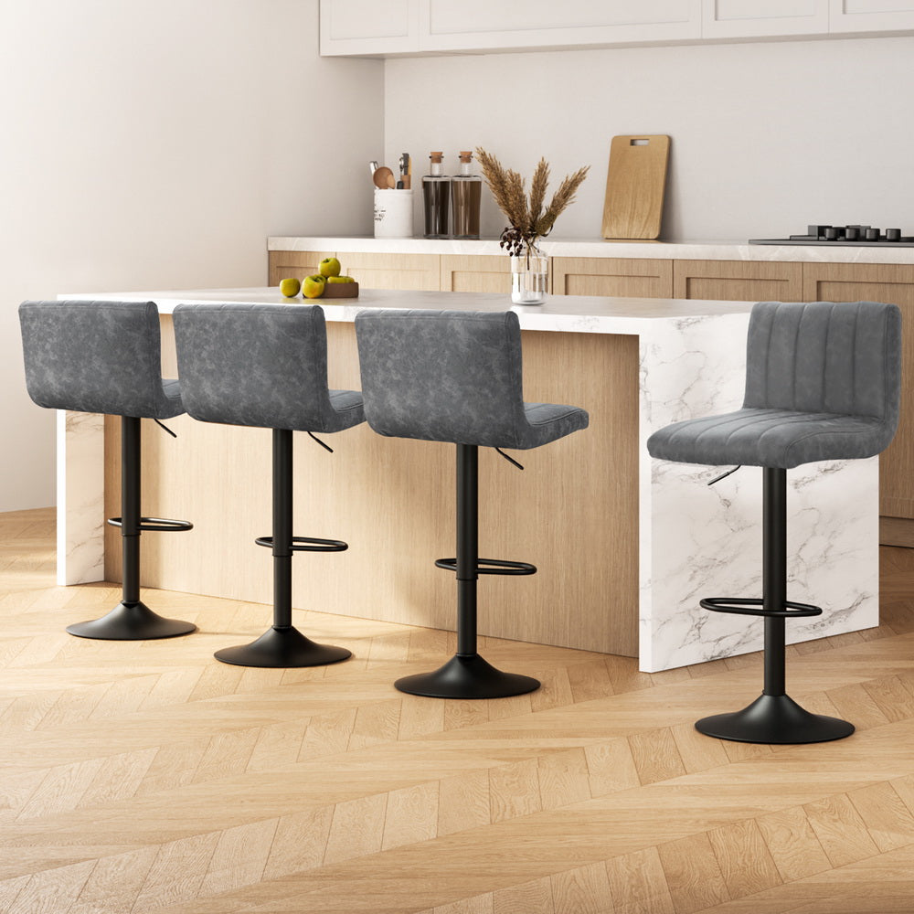 Four gray bar stools with black legs in a modern kitchen setting.