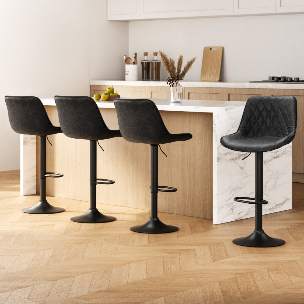 Four black bar stools in a modern kitchen setting with a marble island.