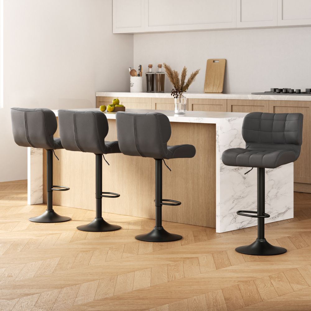 Four black bar stools in a modern kitchen setting with a marble island.