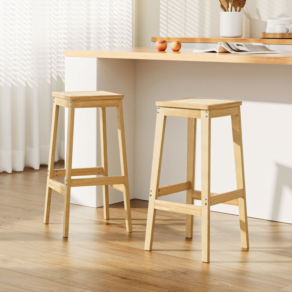 Two wooden bar stools in a room with a table and decor items.