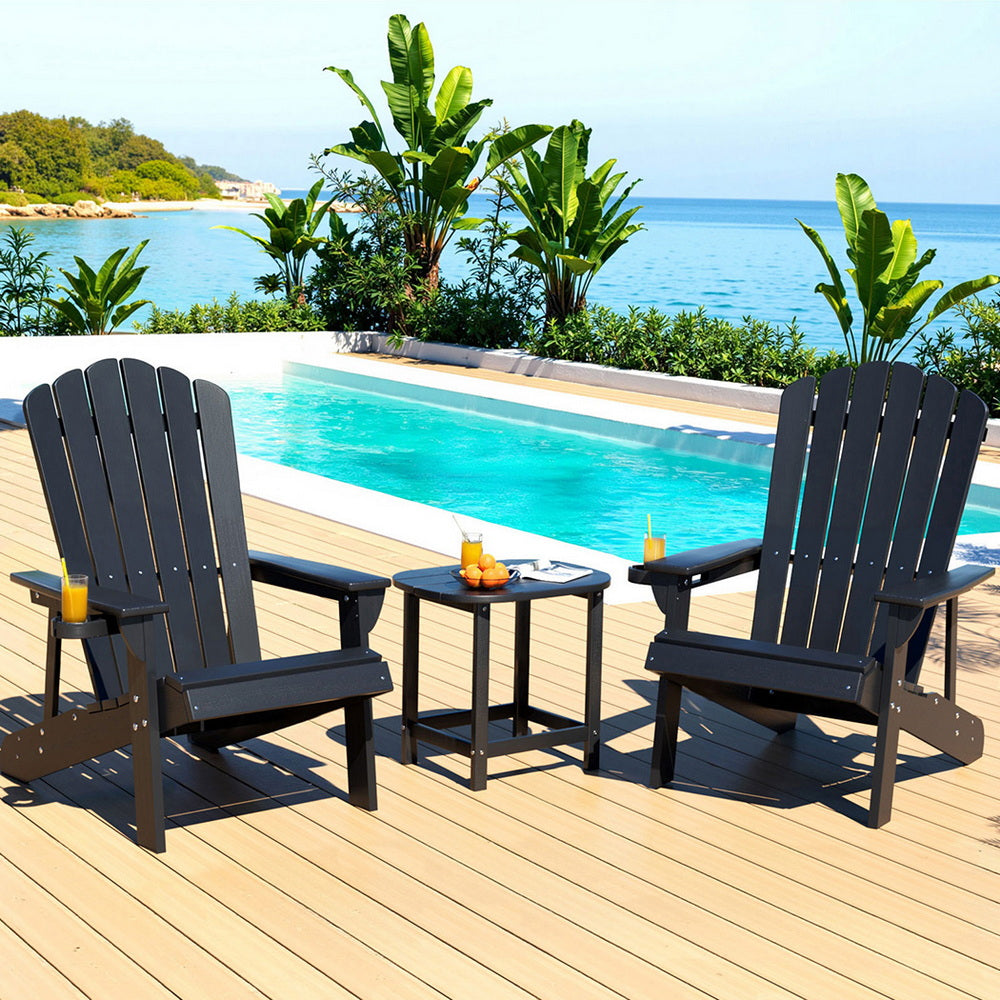 Two dark wooden chairs and a small table by a pool with a scenic background