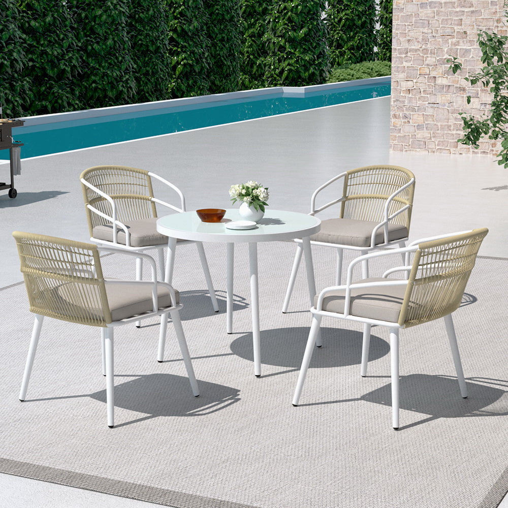Outdoor patio set with table and chairs by a poolside.