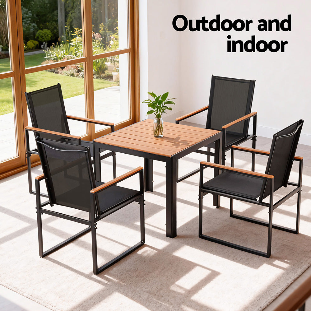 Outdoor and indoor furniture set with a wooden table and black chairs.