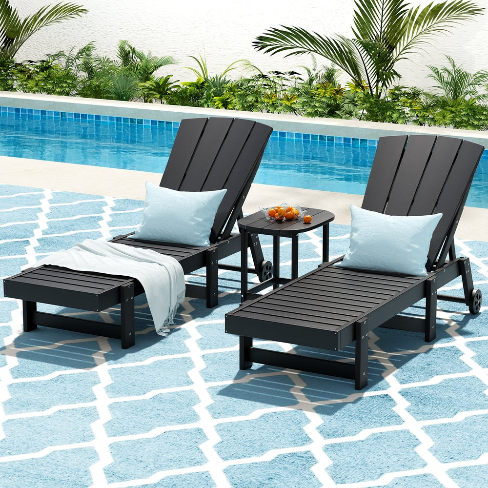 Two black lounge chairs with white cushions by a poolside.