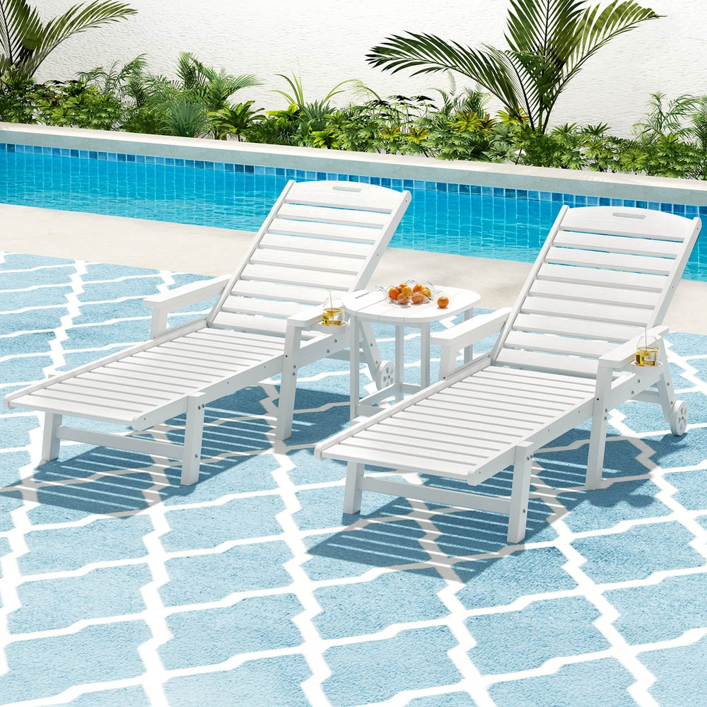 Two white lounge chairs by a pool with a small table between them.