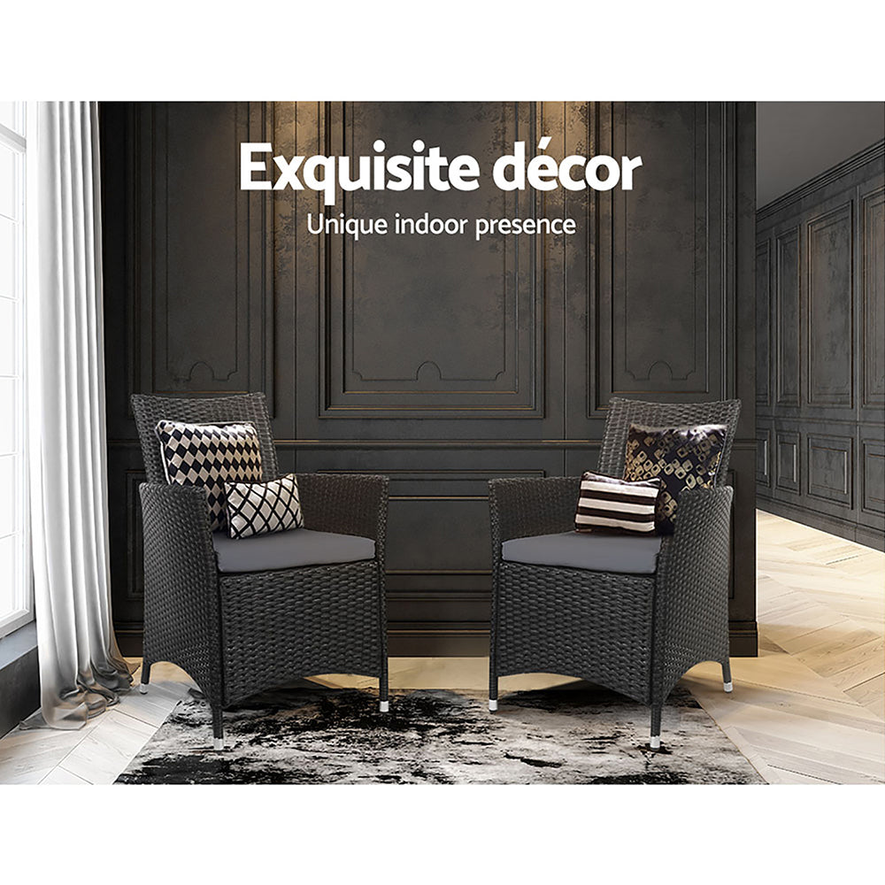 Two wicker chairs with cushions in a room with dark paneled walls and a window.