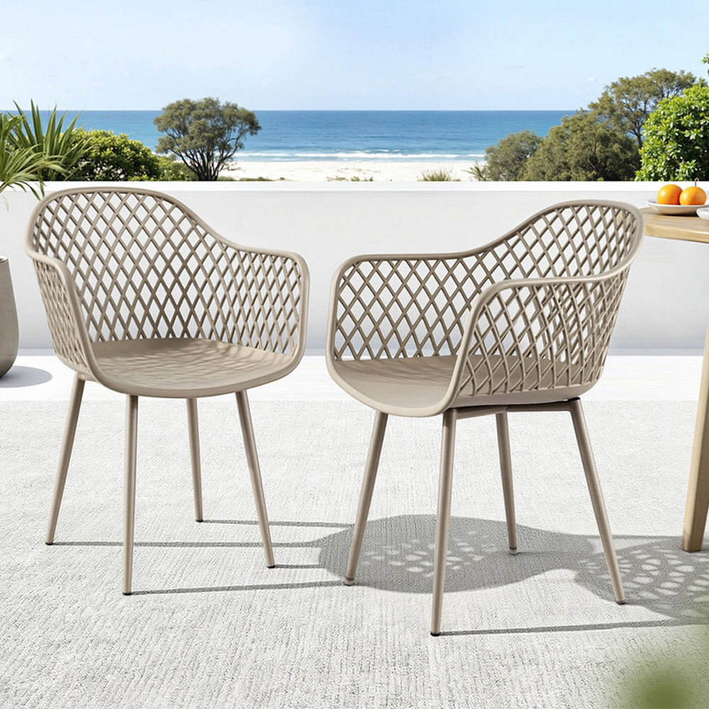 Two beige outdoor chairs with a beach view in the background