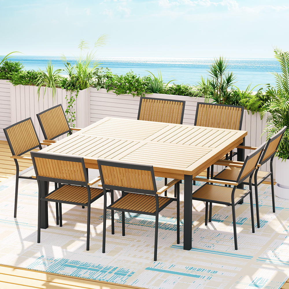 Outdoor dining set with a wooden table and chairs on a patio with a scenic background.