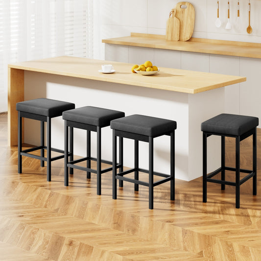 Four black bar stools with gray cushions in front of a wooden kitchen counter.