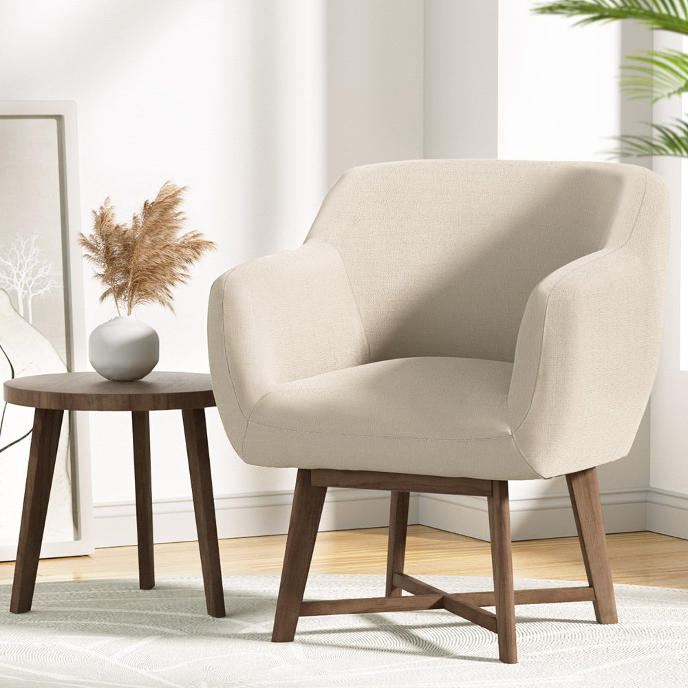 Beige armchair in a room with a wooden side table and decorative elements.