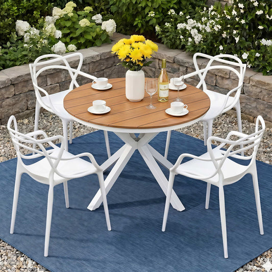 Outdoor dining set with a wooden table and white chairs on a blue rug, surrounded by flowers and a bottle of wine.
