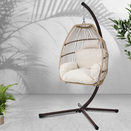 Hanging chair with white cushions on a stand against a light background