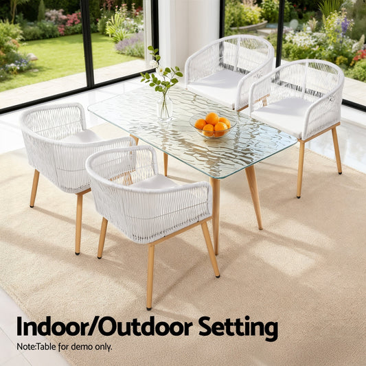 Glass dining table with four white chairs in a modern indoor setting.