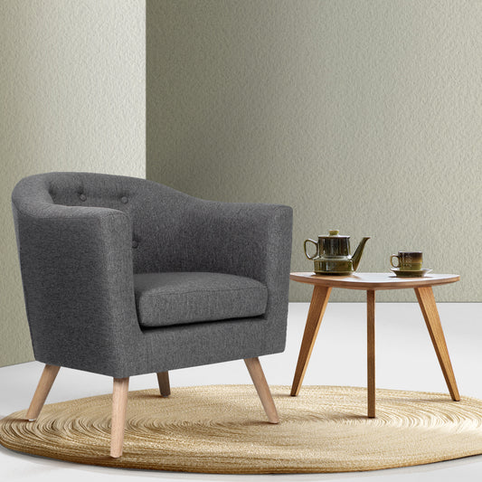 Gray armchair in a room with a small wooden table and teapot.